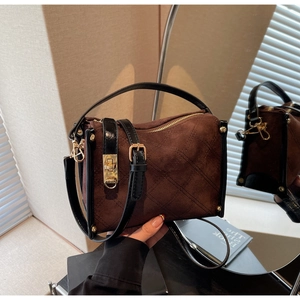 Detailed view of dark brown suede crossbody bag with gold hardware and rhombic pattern