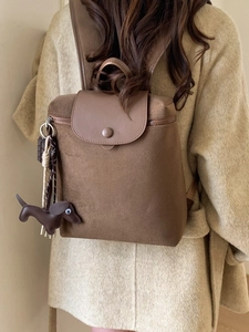 Minimalist large nylon backpack in dark brown worn by model in a natural setting