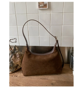 Detailed view of dark brown suede hobo bag with adjustable strap on wooden surface