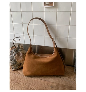 Detail of brown suede shoulder bag with adjustable leather strap and silver zipper