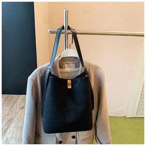 Detail of suede bucket bag with gold turn-lock closure on grey wool coat styling