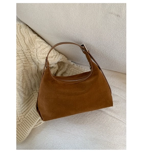 Close-up of brown suede hobo bag with adjustable leather strap on knit fabric background