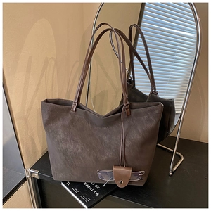 Detail of dark brown matte tote bag with leather glasses holder accessory and dual straps