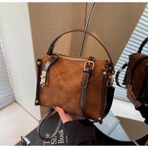 Close-up of brown suede bag featuring diamond quilted stitching and gold hardware