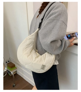 Dettaglio della trama trapuntata a onde e dell'etichetta del marchio della borsa beige