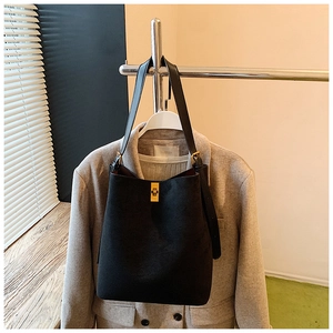 Detail of a black suede bucket bag featuring a refined gold-tone rectangular twist lock closure