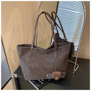 Detail view of coffee brown suede tote bag featuring a creative glasses holder accessory
