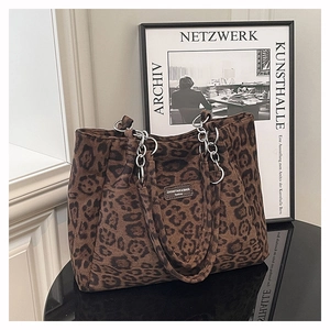 Détail du sac cabas léopard avec poignées en chaîne métallique et écusson de marque