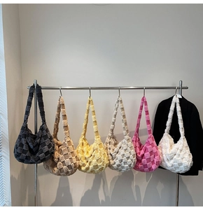 Close-up of plush checkerboard hobo bags hanging in various colors on a rack