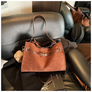 Detail of caramel suede tote bag with metal twist lock and cute plush bear charm