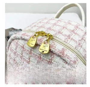 Close-up of golden zippers and textured pink tweed fabric on a stylish backpack