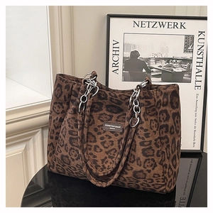 Détail du sac cabas léopard avec bandoulière chaîne et étiquette sur tissu daim