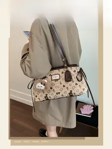 Detail of printed leather tote bag with a cute plush bear pendant and adjustable strap