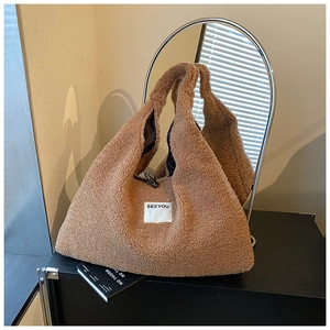 Brown fleece tote bag detail showing SEEYOU label and horn buckle on a black cabinet