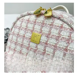 Close-up of pink and white tweed fabric with golden metallic zipper and brand logo