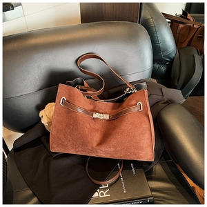 Detail of vintage brown suede tote bag with dark leather strap and silver metal lock