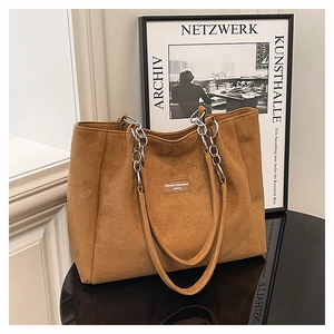Détail du sac cabas en suède avec poignée en chaîne métallique et écusson logo carré