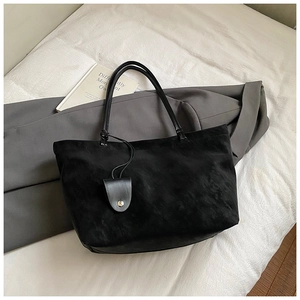 Close-up of black suede tote bag on white fabric with minimalist commuter aesthetic