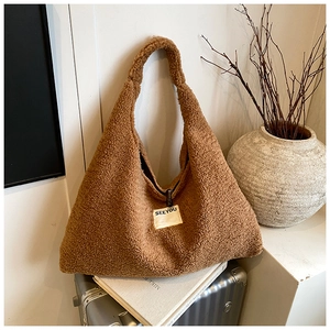 Detail of brown teddy fleece tote bag featuring a white SEEYOU patch on a metal suitcase
