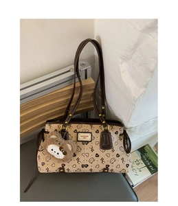 Detail view of beige patterned tote bag with bear print and luxury leather handle