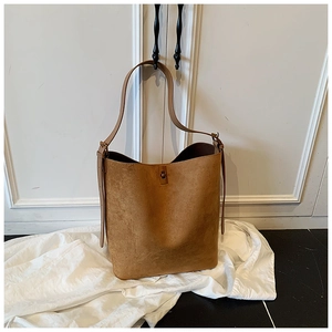 Detailed view of brown suede bucket bag featuring adjustable strap and vintage buckle
