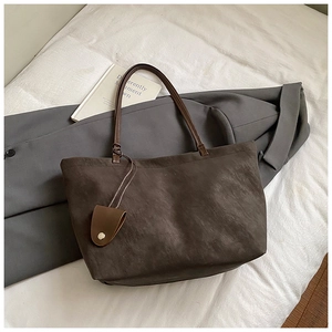 Detailed close-up of a large dark brown matte PU leather tote bag on a stylish blazer