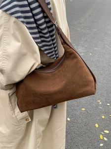 Deep brown suede hobo bag with adjustable leather strap worn by a model in a trench coat