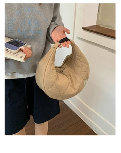 Dettaglio borsa a mezzaluna trapuntata beige con cuciture a onda e fibbia a scatto