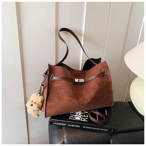 Detail of vintage brown suede tote bag with leather strap and cute bear charm