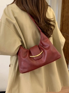 Elegant red PU leather dumpling bag with golden crescent buckle on model with trench coat