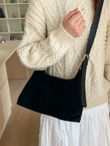 Minimalist black suede crossbody shoulder bag with silver buckle worn by a model in white