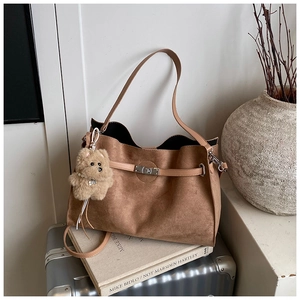 Detail of coffee brown suede tote bag with leather straps and cute plush bear charm