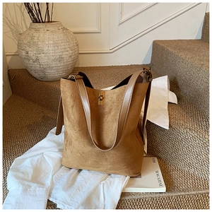 Detail shot of a brown suede bucket bag with a golden rectangular twist-lock closure