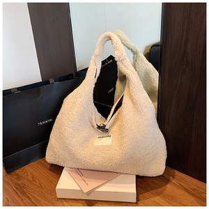 Detailed view of cream sherpa tote bag with toggle closure and See You label on wood