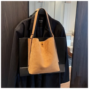 Detail of camel suede bucket bag featuring a metal turn-lock closure and slim shoulder strap