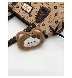 Close-up of brown tote bag with heart patterns and a cute animal plush charm accessory