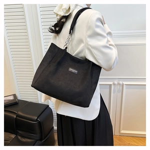 Détail du sac cabas noir avec bandoulière en chaîne argentée et étiquette de marque