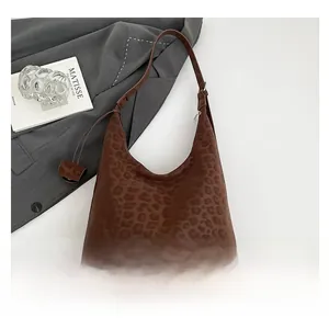Detail of leopard print tote bag on grey blazer with artistic book and glass decor
