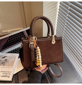 Détail du sac bandoulière en daim marron avec poignées tressées et logo gaufré KXO DEOR