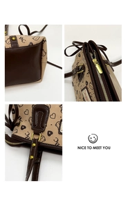 Detail view of beige canvas tote with cat prints, brown leather trim and gold hardware