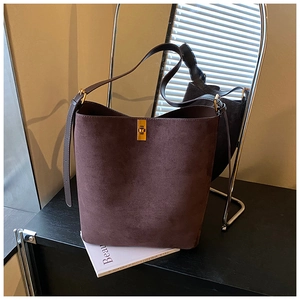 Detail of dark brown suede bucket bag with gold swivel lock and adjustable strap