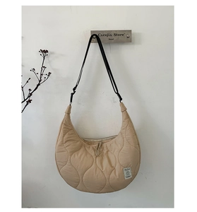 Dettaglio della borsa a mezzaluna beige trapuntata a cuore con tracolla nera regolabile