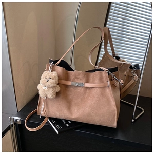 Detail of vintage brown suede tote bag with silver metal clasp and plush bear charm