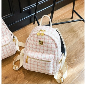 Close-up of pink tweed texture and gold logo plate on women backpack for work