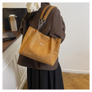 Détail d'un grand sac cabas en daim marron avec décoration de chaîne en argent chic