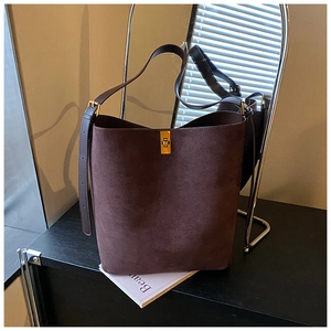 Close-up of brown suede bucket bag featuring a golden rectangular clasp and leather strap