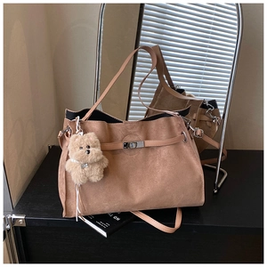 Detailed view of dark brown frosted tote bag with metal twist lock and cute bear pendant