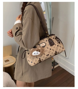 Close-up of beige tote bag with brown bear print pattern and metal logo plate detail
