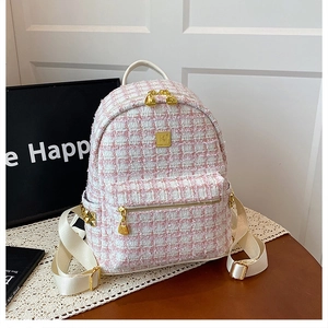 Detail of pink and white tweed backpack with gold metal zippers and leather straps