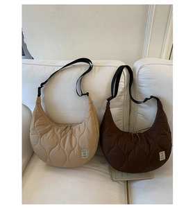 Borse hobo trapuntate beige e marroni con tracolla regolabile su un divano bianco